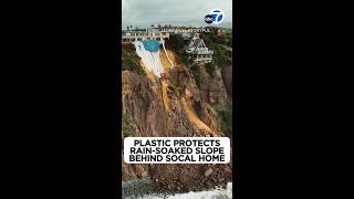 Plastic protects rain-soaked slope behind SoCal home